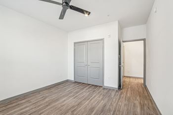 An empty living room with a ceiling fan and a door to a closet